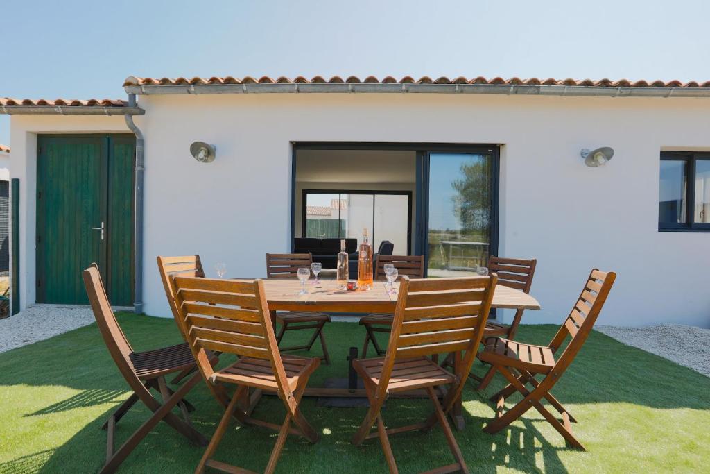 a wooden table and chairs on a patio at Maison tout confort a deux pas de la piste cyclable in Le Bois-Plage-en-Ré