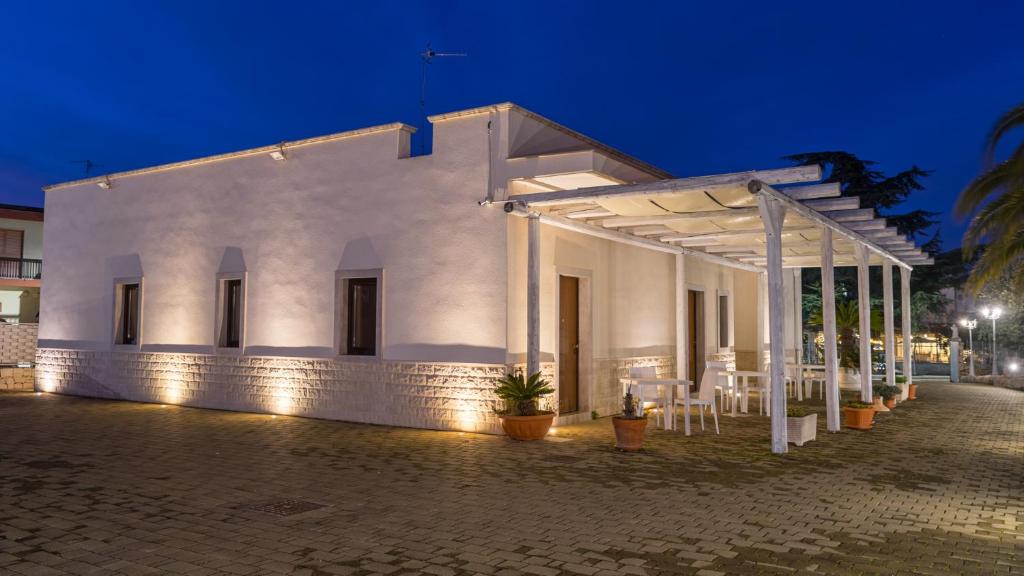 a white building with tables and chairs at night at Dimora Delle Grotte in Castellana Grotte