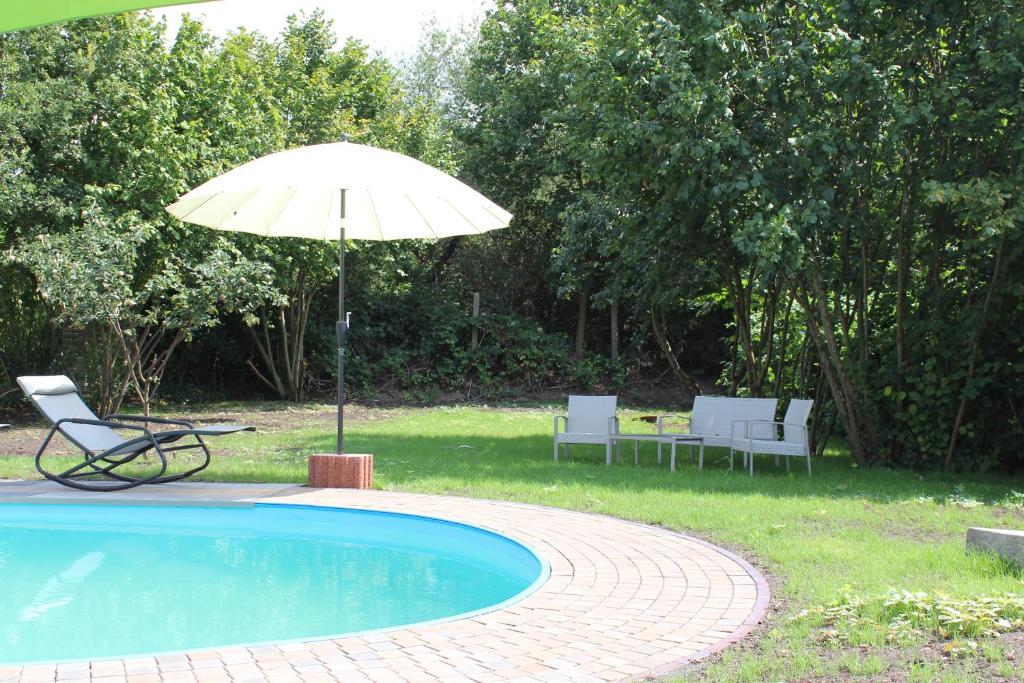 an umbrella and chairs next to a swimming pool at Villa Bademeusel in Straupitz