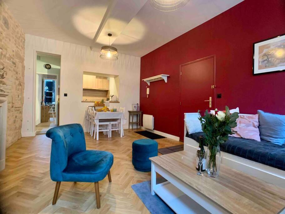 - un salon avec un canapé bleu et un mur rouge dans l'établissement Hello Bayeux - Confort dans le coeur de la ville, à Bayeux