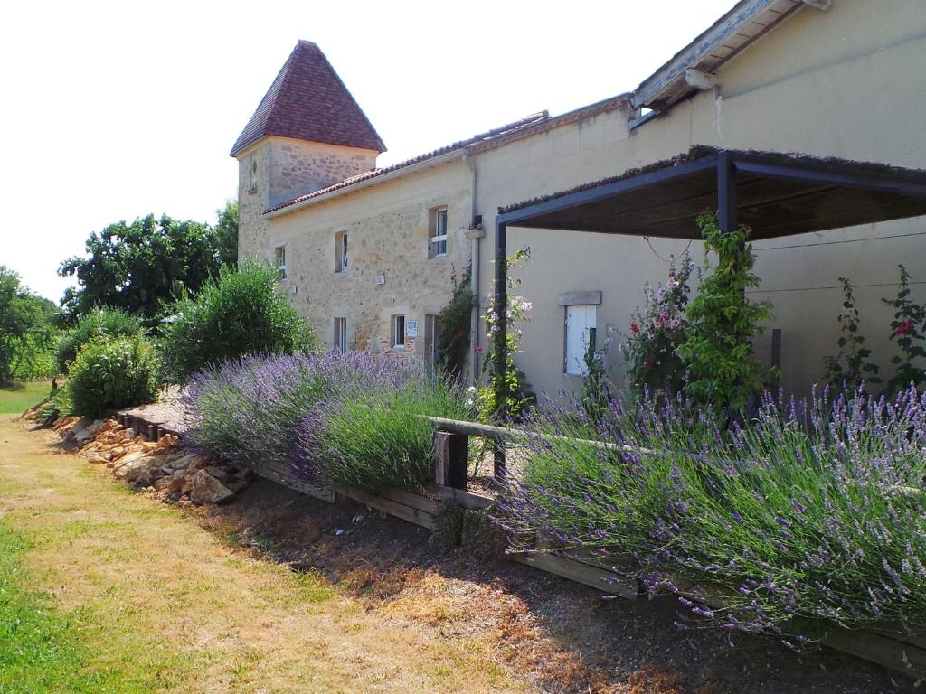 un edificio con flores púrpuras delante de él en Beautiful holiday home with swimming pool, en Monprimblanc