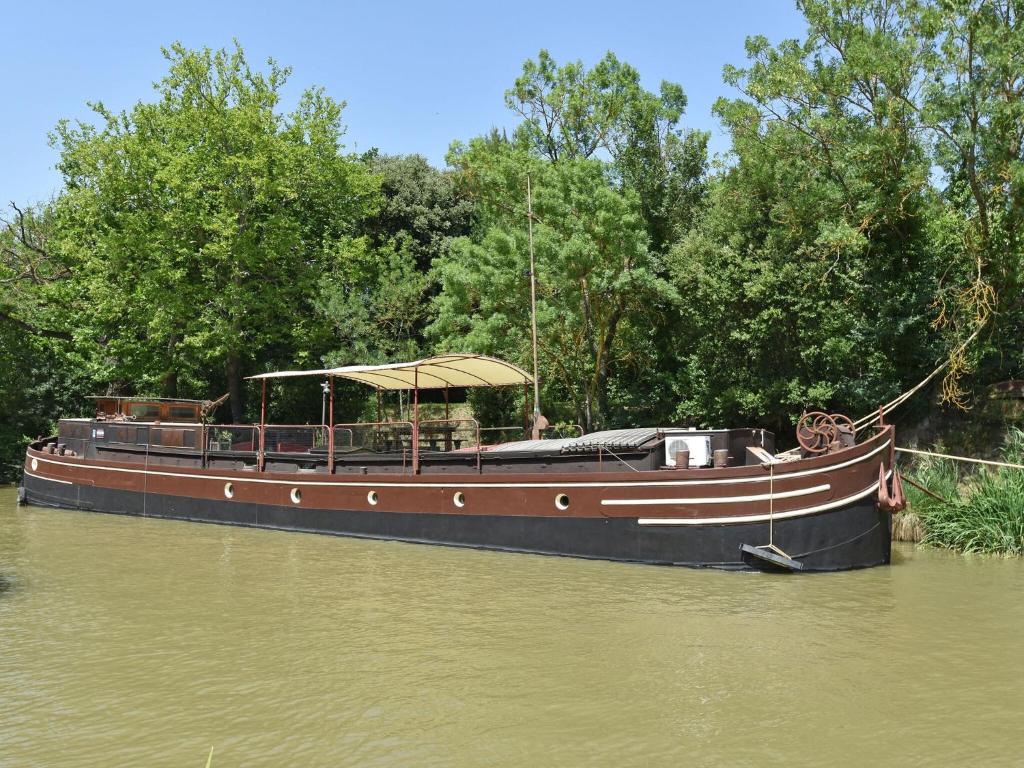 a boat with an umbrella sitting in the water at Charming Boat in Villedubert with Terrace in Villedubert