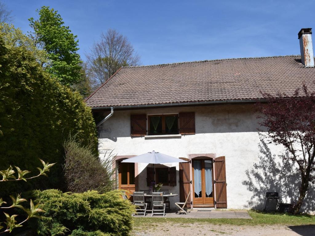 a white house with a table and an umbrella at Holiday home in Saulxures sur Moselotte in Saulxures-sur-Moselotte