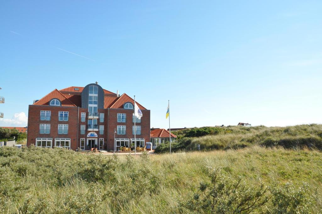 ein Gebäude am Strand mit einem Grasfeld in der Unterkunft Strandhotel Juister Hof in Juist