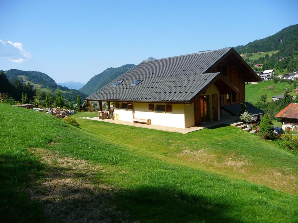 a house with a black roof on a green field at Sunny Chalet in Les Gets with Jacuzzi in Les Gets