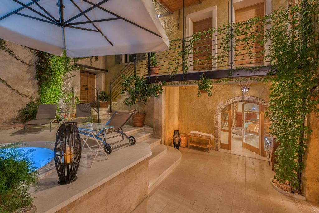 Corte Alma Spa and Luxury Home في غارغنانو: فناء في الهواء الطلق مع مظلة وحوض استحمام ساخن