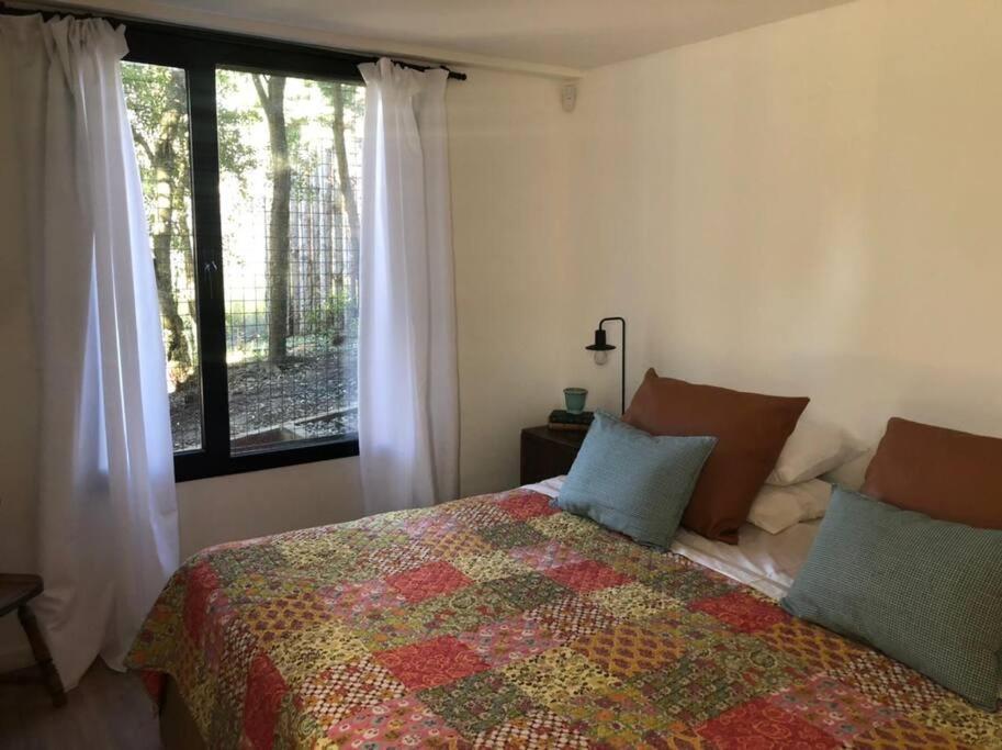 a bedroom with a bed with a quilt and a window at Cabaña en COMPLEJO DEL ARROYO - Bariloche KM 11 in San Carlos de Bariloche