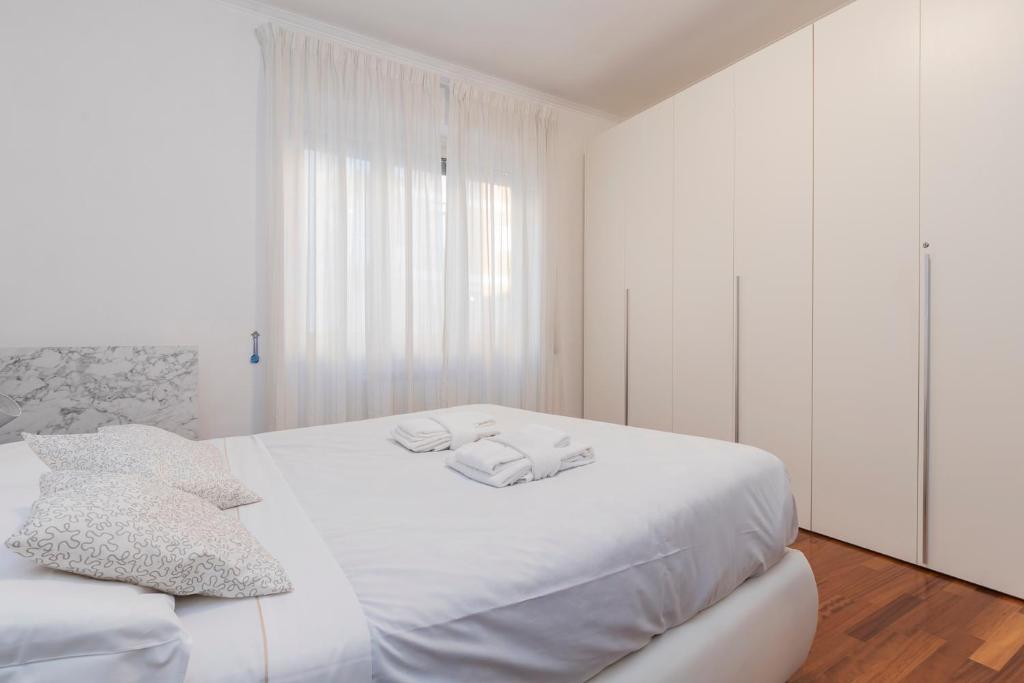 una camera bianca con un grande letto con due asciugamani di Casa Samy - Sesto SG a due passi da Sesto Rondò - Battisti a Sesto San Giovanni