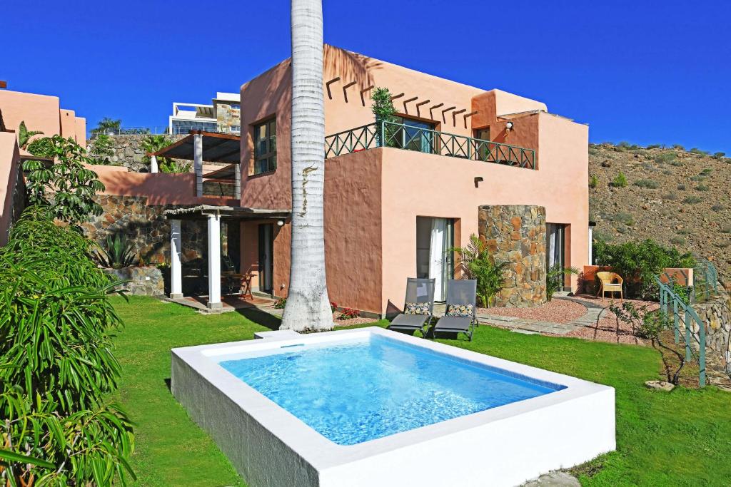 a villa with a swimming pool in front of a house at Salobre Morro Golf 2 in Maspalomas