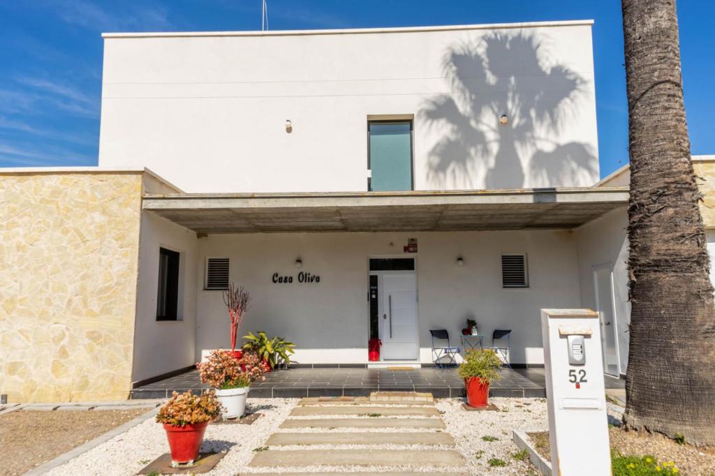 a white building with a palm tree in front of it at Casa Oliva 52 in Seville