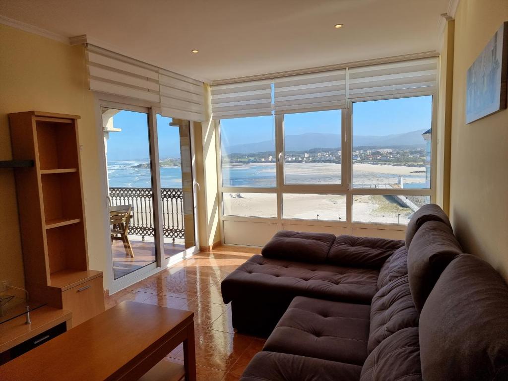 sala de estar con sofá y vistas a la playa en Dúplex en 1ª línea de playa, en Foz