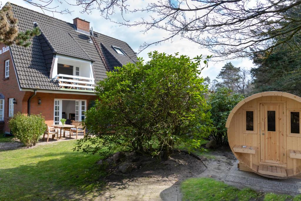 a house with a wooden door in the yard at Strandhüs Family in Wenningstedt