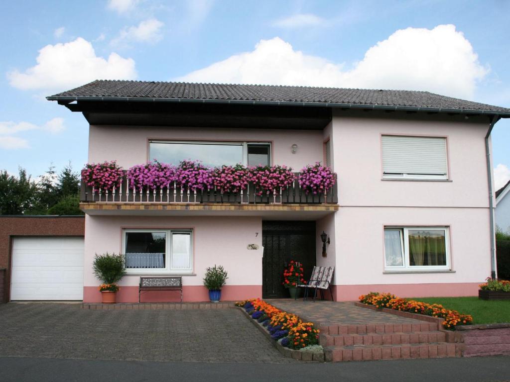 a white house with purple flowers on a balcony at Apartment in the centre of the Eifel in Strotzbüsch