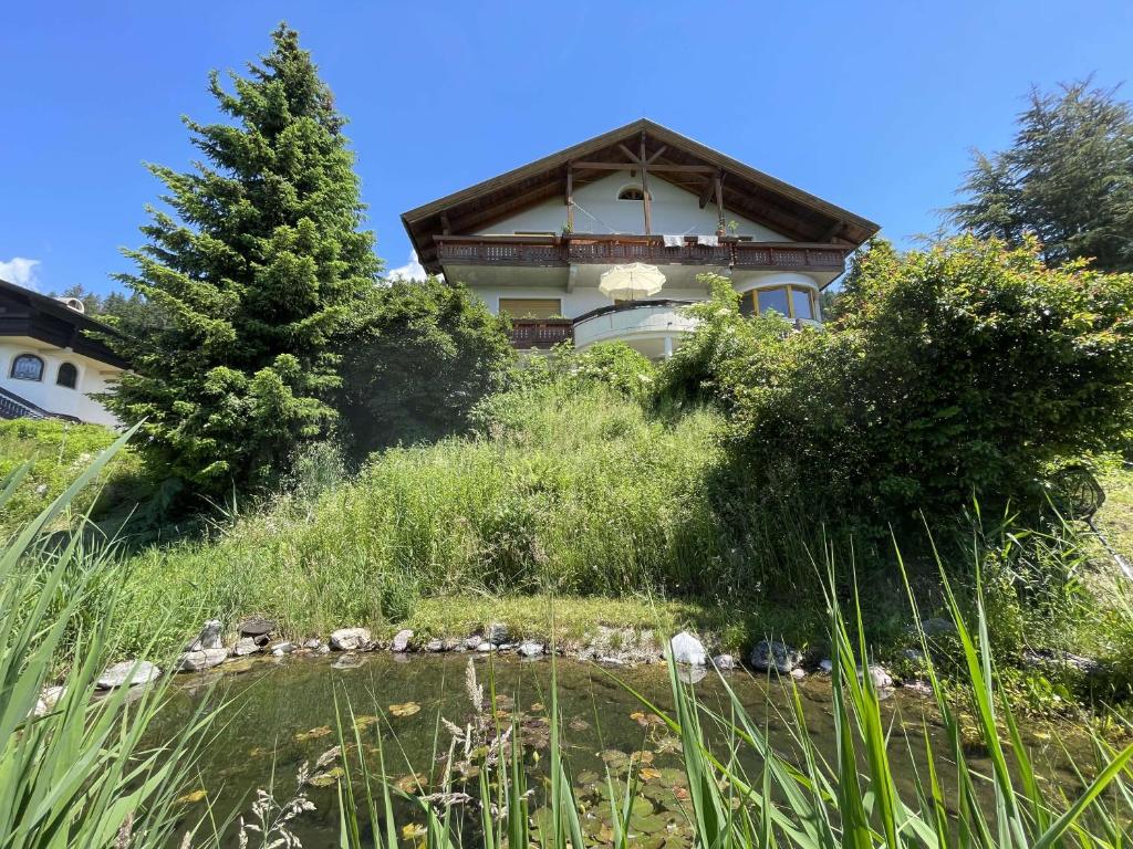 una casa en la cima de una colina con un estanque en Casa de la Paz, Millstatt - geräumige neu ausgestattete FeWo mit Seeblick und Bergpanorama, en Millstatt