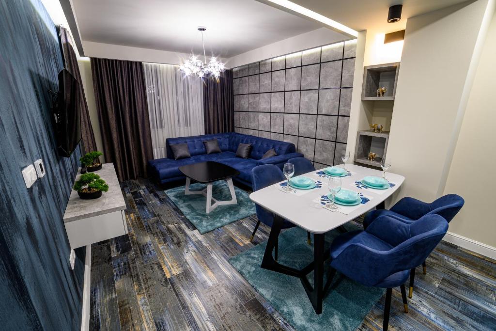 a living room with a table and blue chairs at Apartmani Milanovic in Bijeljina