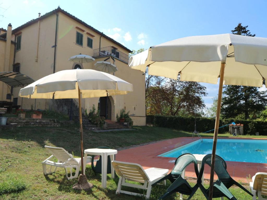 een groep parasols en stoelen naast een zwembad bij Belvilla by OYO Villa Gaio in Vicchio