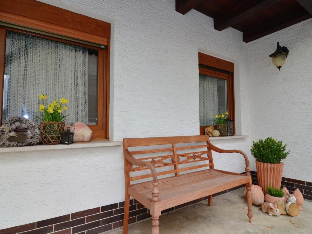 a wooden bench sitting on a porch next to a window at Wonderful apartment with barrel sauna in Stockheim