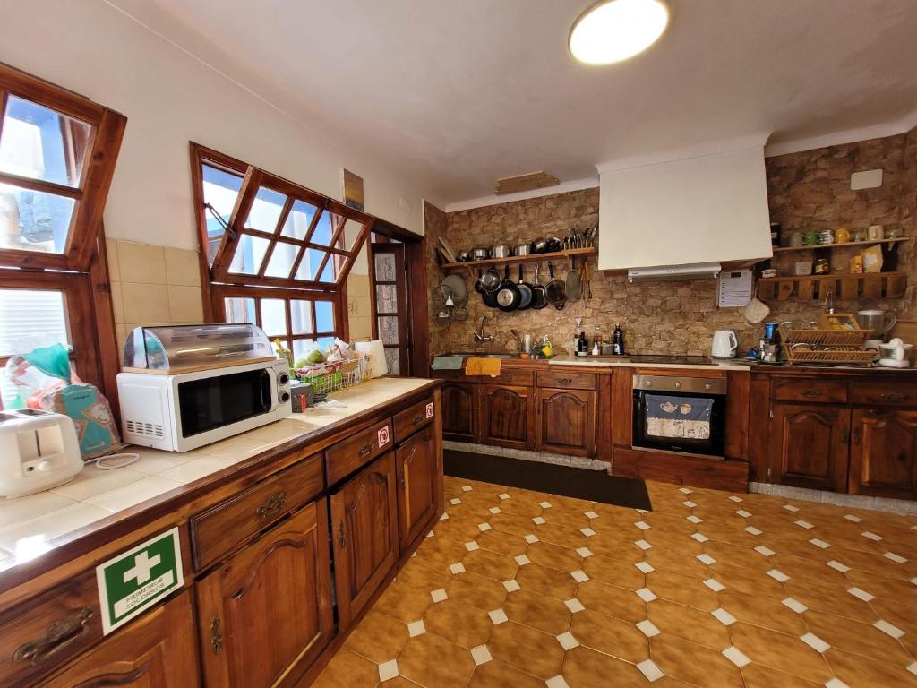 a large kitchen with wooden cabinets and a microwave at The Handmade House Azores in Porto Formoso