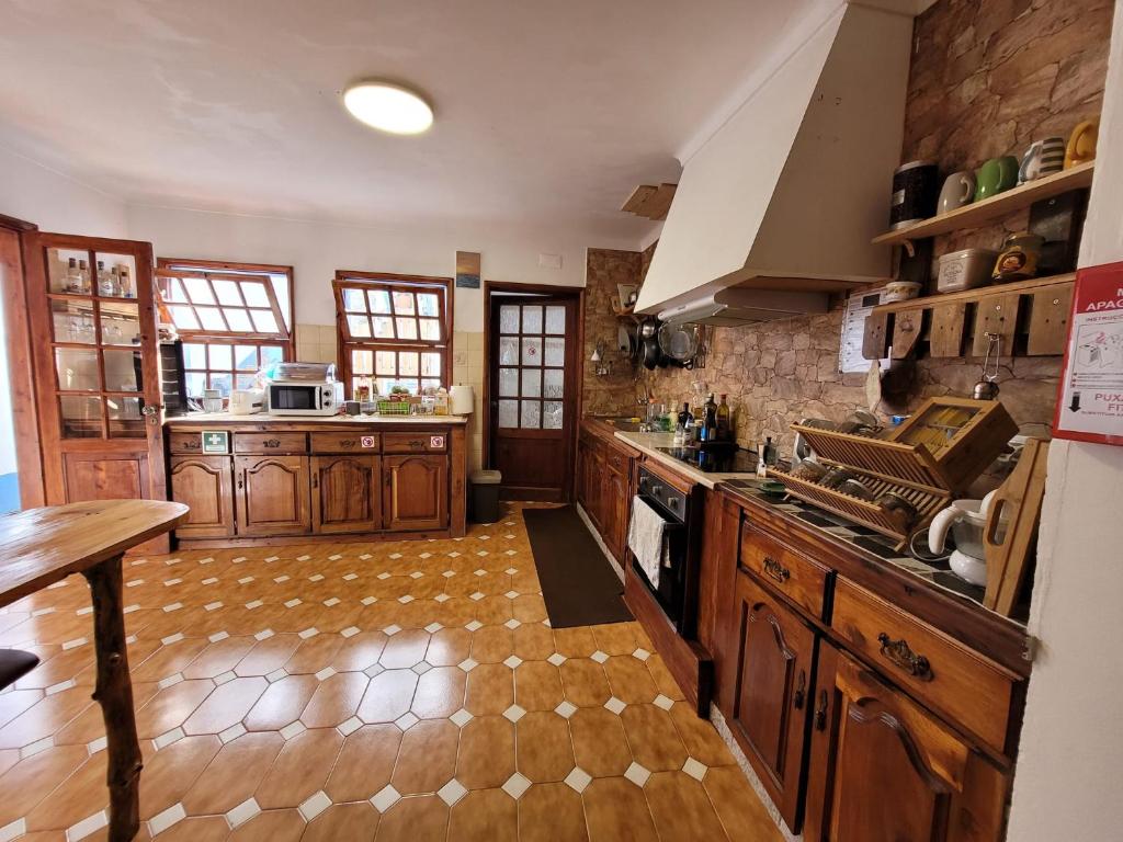 a large kitchen with wooden cabinets and a wooden floor at The Handmade House Azores in Porto Formoso