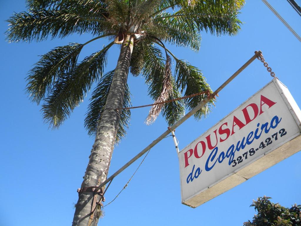 a sign for a restaurant hanging from a palm tree at Pousada do Coqueiro in Urubici