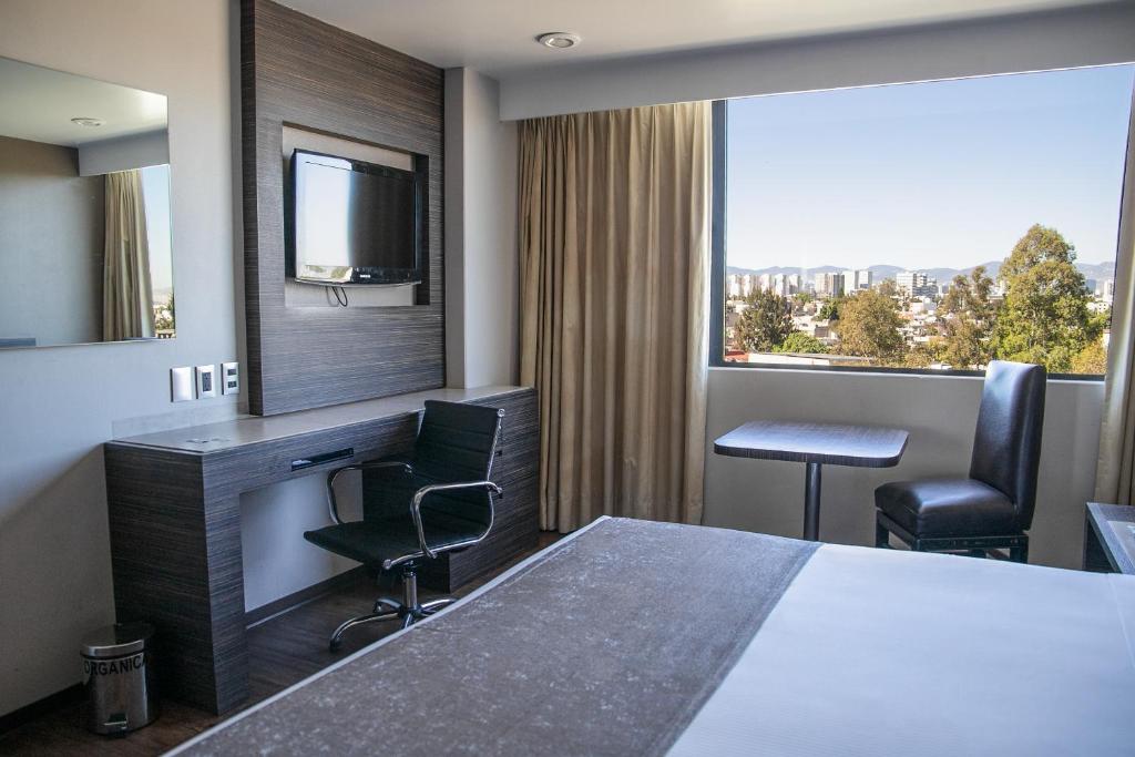 Habitación de hotel con cama, escritorio y TV. en Hotel Brasilia en Ciudad de México