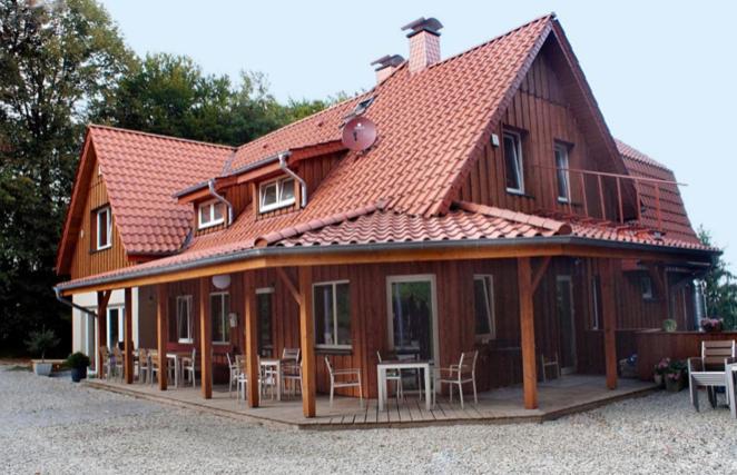 a large wooden house with tables and chairs on it at Berggasthof Tönsblick in Oerlinghausen