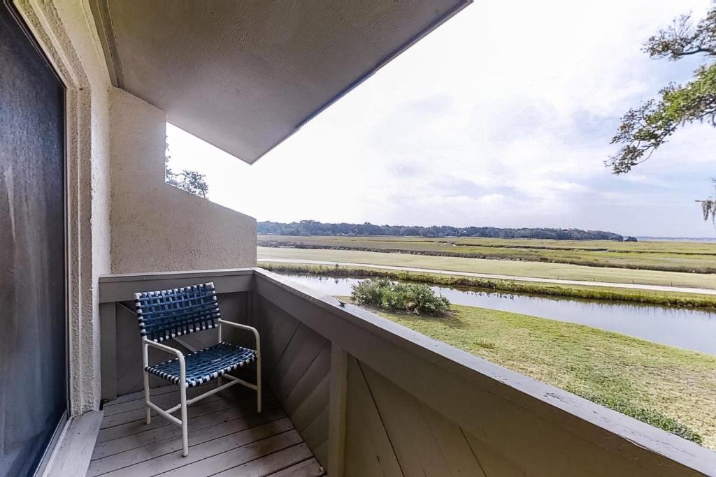 Amelia Island Plantation townhome with amazing marsh views, WiFi & shared pool في Franklintown: كرسي على شرفة مطلة على نهر