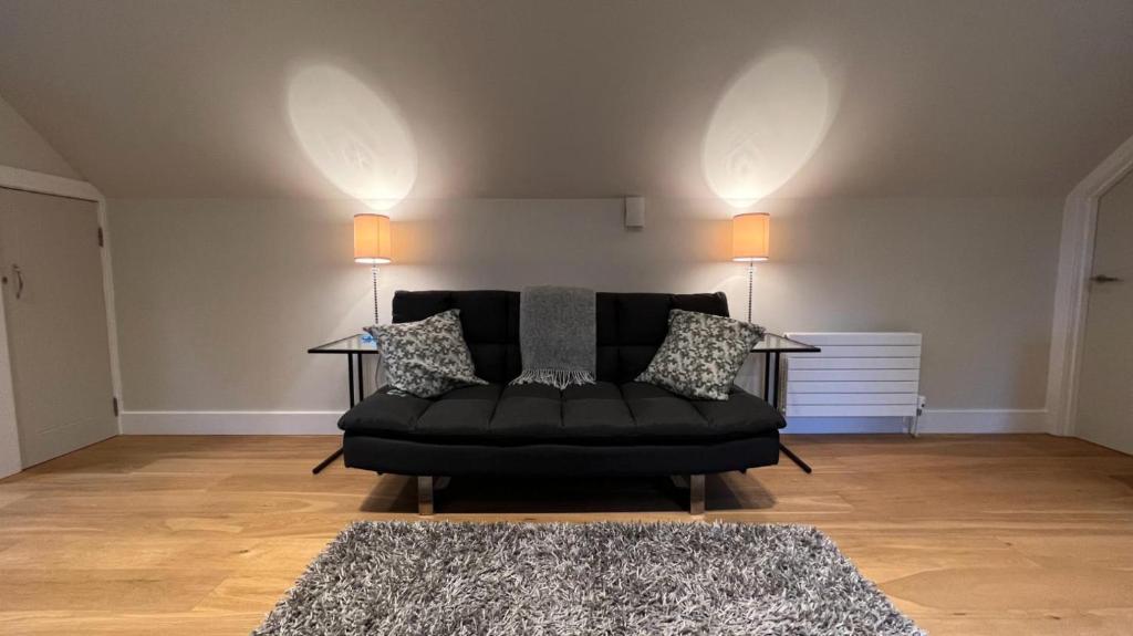 um sofá preto numa sala de estar com dois candeeiros em NEW 1BD Contemporary Flat Upper Dunblane em Dunblane