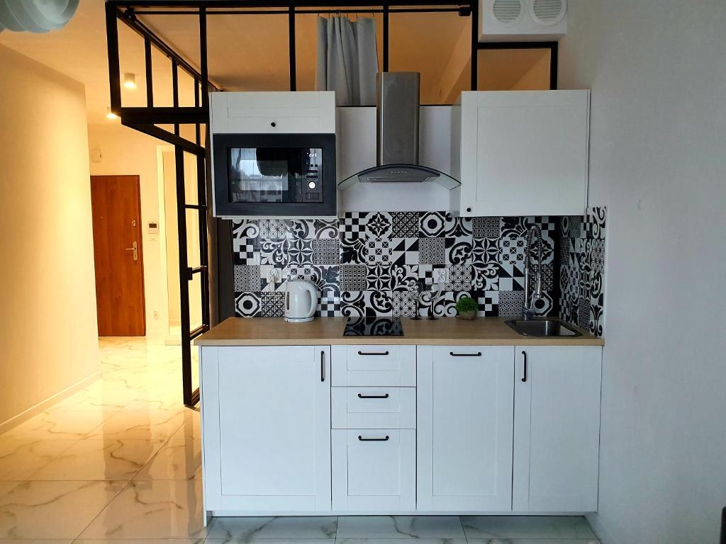 a kitchen with white cabinets and a black and white wallpaper at Apartament Ania Stare Miasto in Elblag