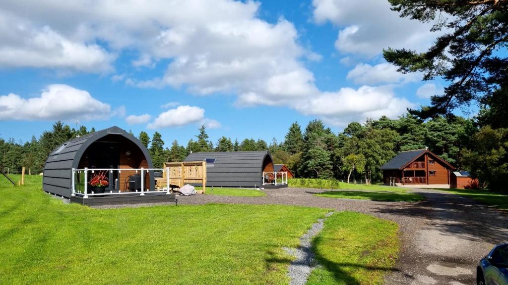 a barn and a house on a grass field at Robins Nest Glamping Pod with Hot Tub in Keith