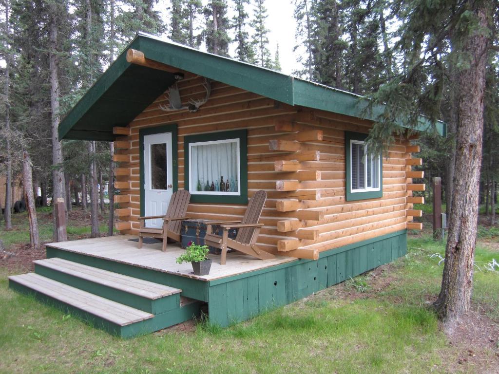 a log cabin with two chairs and a table on a deck at Six Mile River Resort in Tagish