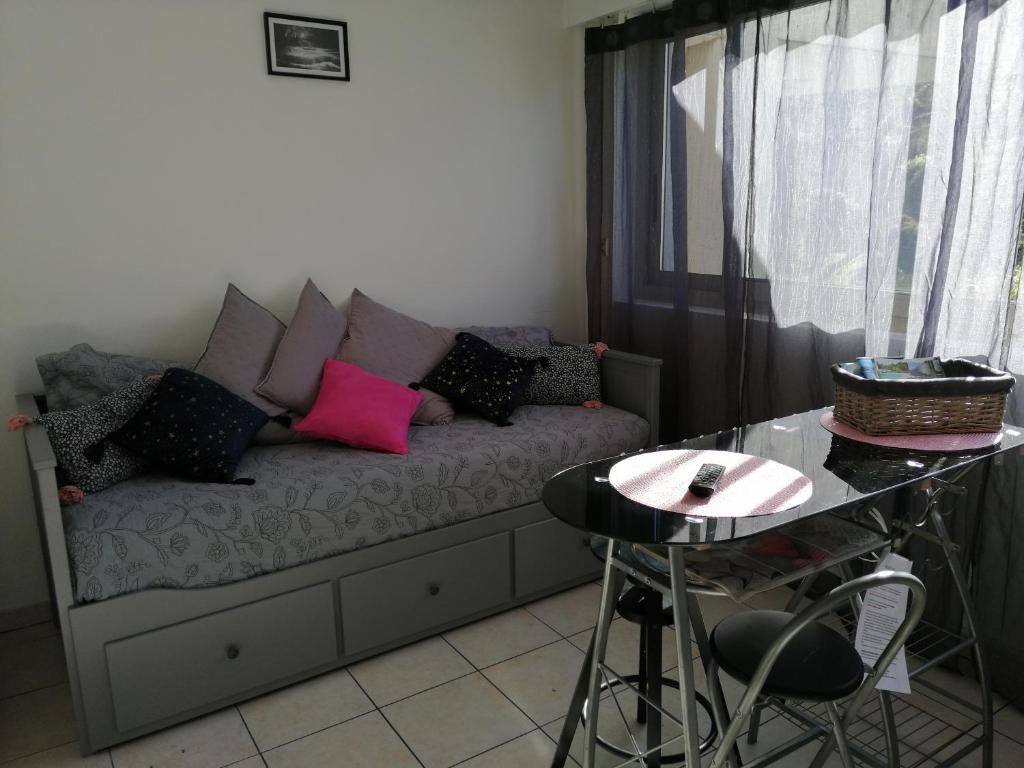 ein Wohnzimmer mit einem Sofa mit Kissen und einem Tisch in der Unterkunft STUDIO MARINA BAIE DES ANGES in Villeneuve-Loubet