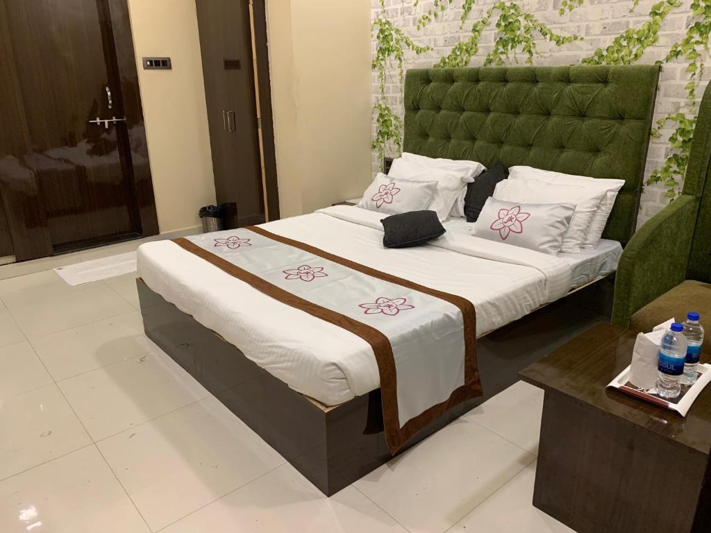 a bedroom with a large bed with a green headboard at JK Rooms 126 Parashar Legacy - Opp Railway Station in Nagpur