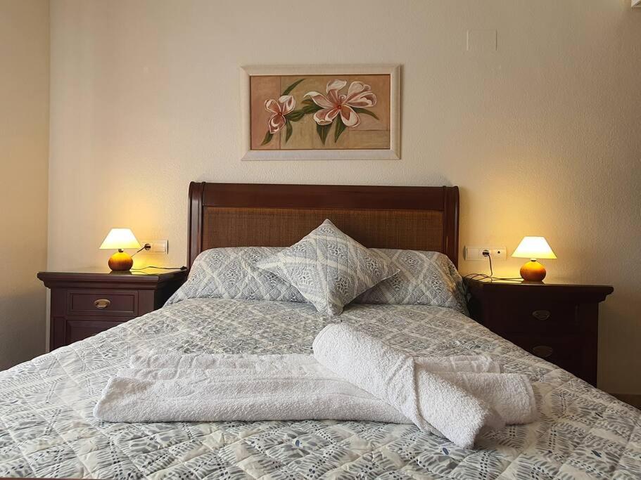 Apartamento Ribera Real II في قرطبة: سرير مع لحاف أبيض ومصباحين