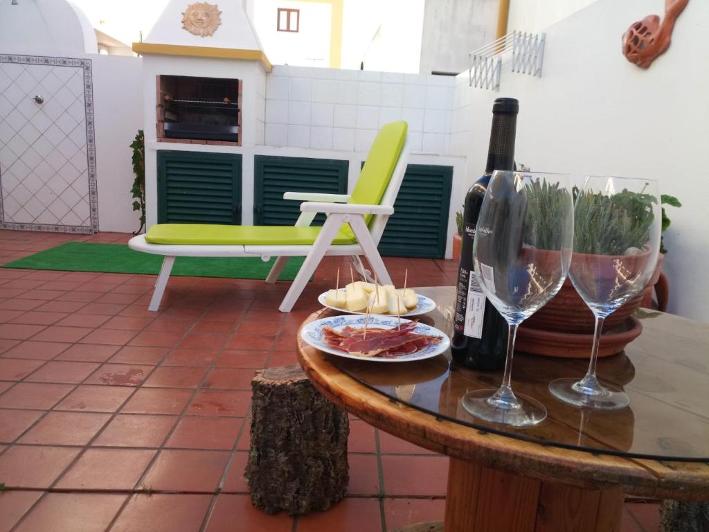 a table with a bottle of wine and wine glasses at Silva's House in Vila Nova de Milfontes