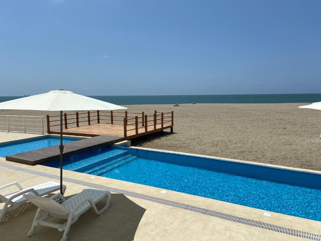een zwembad naast een strand met een parasol bij Ocean Club - Ocean Suites II in Playas