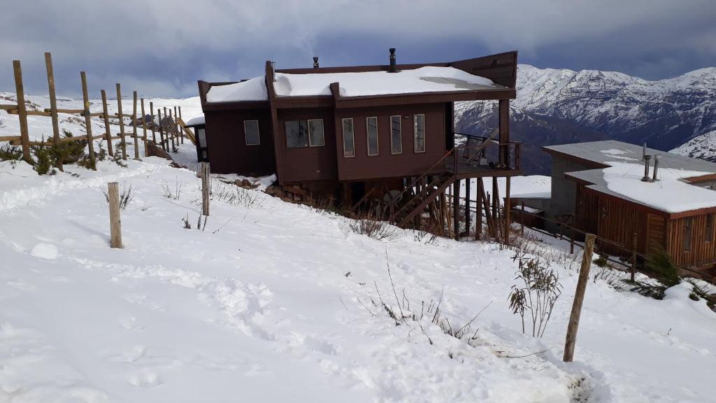 a cabin in the snow with a fence and mountains at Casa en Farellones in Santiago