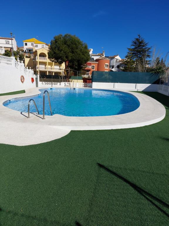 una gran piscina con césped verde y edificios en Casa lunera, en Mijas Costa