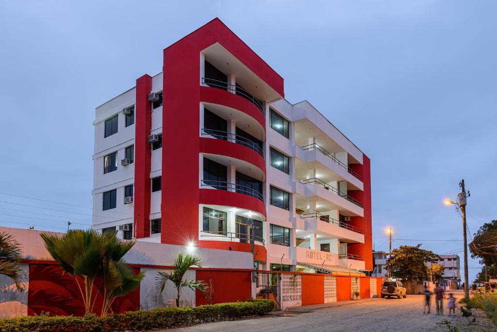 um edifício de apartamentos vermelho e branco numa rua em Hotel RC Tonsupa em Tonsupa