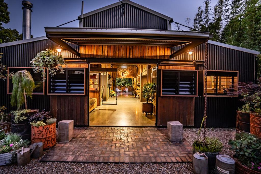 an exterior view of a house with a brick driveway at The Bangalow Barn in Bangalow