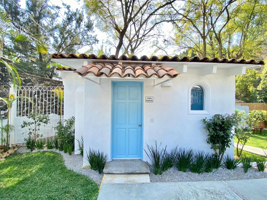 a small white house with a blue door at Hotel Cala Blanca Cuernavaca in Cuernavaca