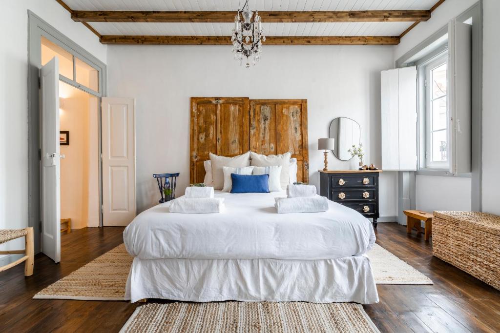 una camera da letto con un grande letto bianco e un lampadario a braccio di Al Sharaz - Dazzling Cottage in Alentejo a Reguengos de Monsaraz