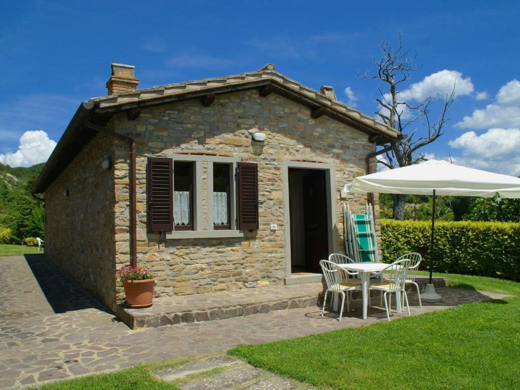 una piccola casa in pietra con tavolo e ombrellone di Beautiful apartment with private terrace and panoramic swimming pool a Parnacciano