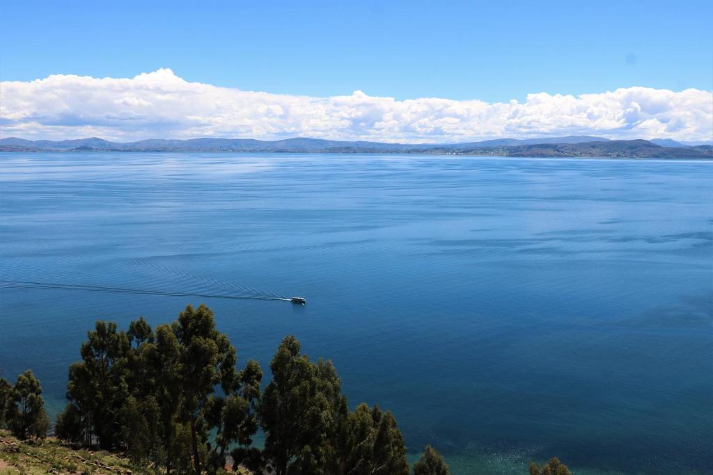 TAQUILE LODGE - Un lugar de ensueño في Huillanopampa: تجمع كبير للمياه مع وجود قارب فيه