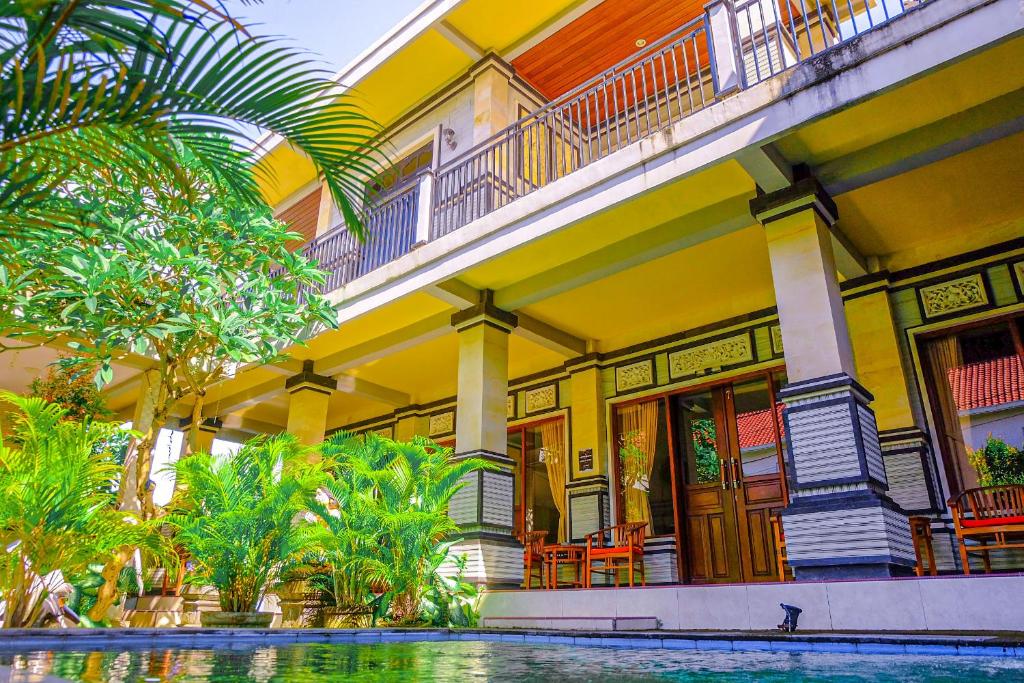 a yellow building with a pool in front of it at Adi Homestay in Canggu