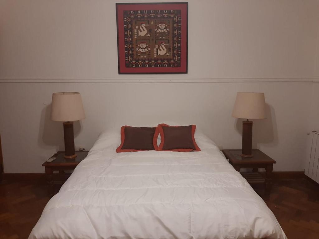 a bedroom with a white bed with two lamps at Casa frente al parque San Martín zona residencial in Mendoza