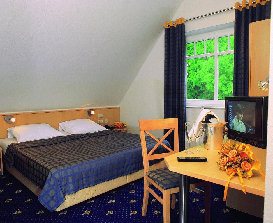 a bedroom with a bed and a desk with a television at Hotel Restaurant Lathener Marsch in Lathen
