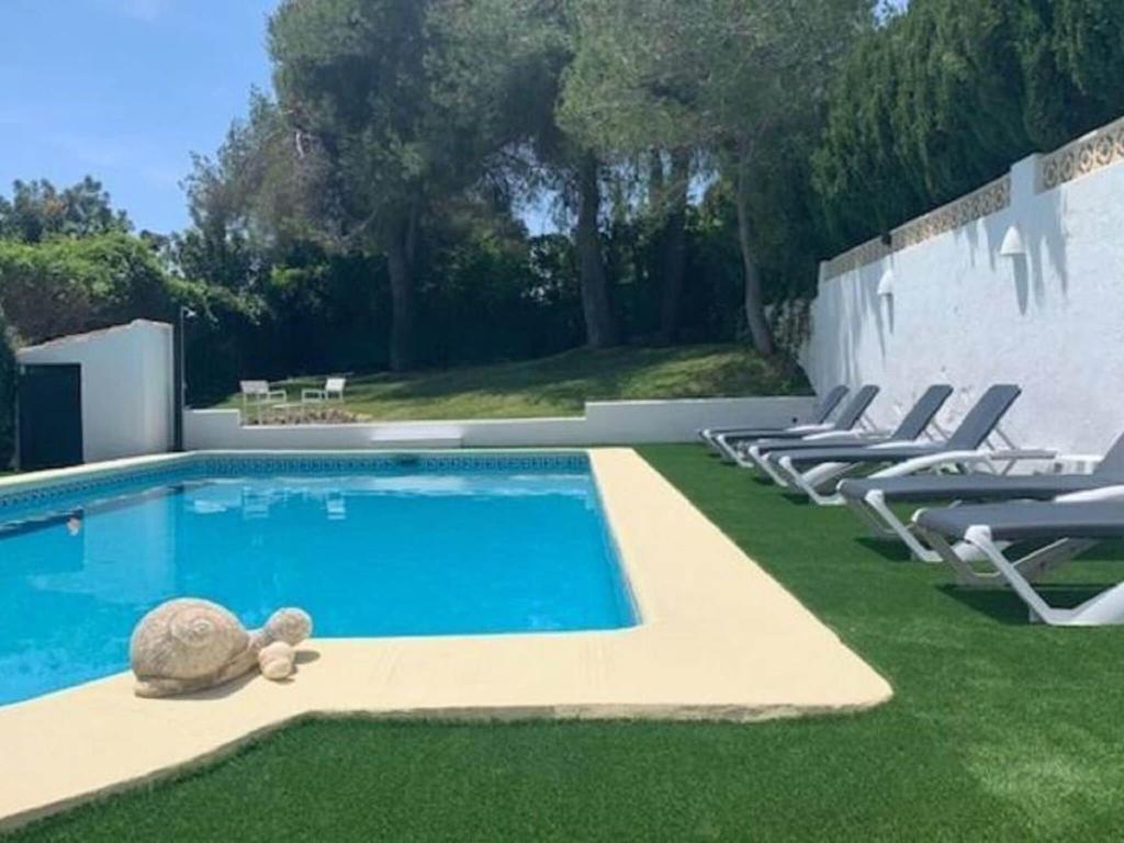 a pool with chairs and a turtle on the grass at Belvilla by OYO Villa Rivas in Jávea