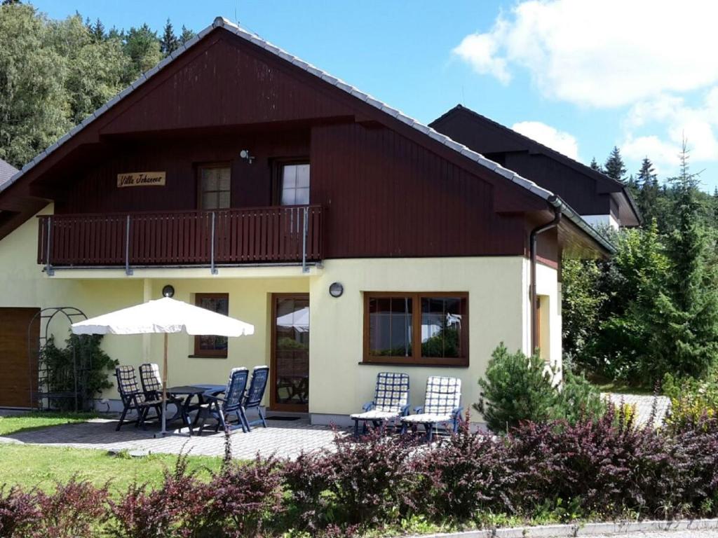 a house with chairs and an umbrella in front of it at beautiful villa at the Lipno Lake with ski pistes in Kramolín