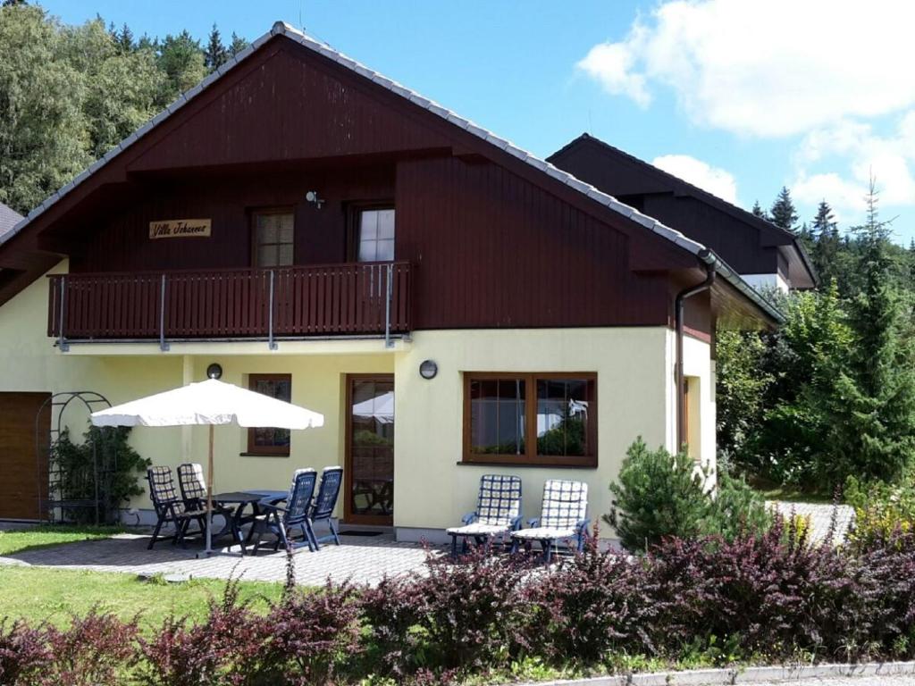 une maison avec des chaises et un parasol devant elle dans l'établissement beautiful villa at the Lipno Lake with ski pistes, à Kramolín